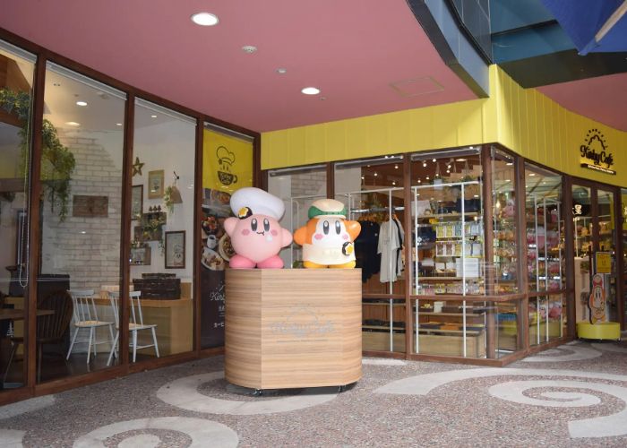 Kirby and a Waddle Dee greeting you at the entrance of a Kirby Cafe.
